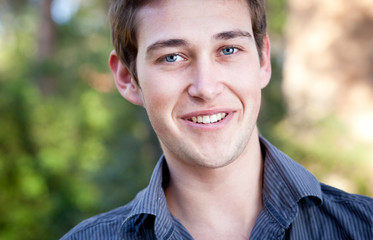 close-up portrait of a casual handsome man smiling while outdoor