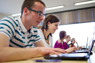Obraz premium college students sitting in a classroom, using laptop computers