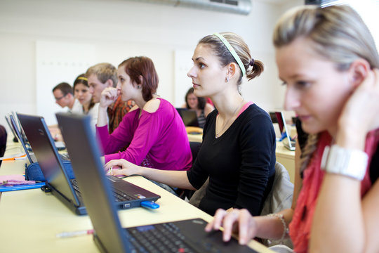 college students sitting in a classroom, using laptop computers