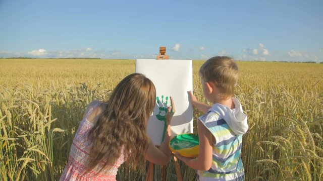 Woman with little boy drawing with fingers in the field