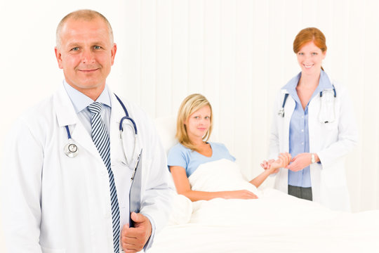 Two doctors with patient lying in bed