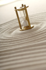 Sanduhr im Sand mit Spuren