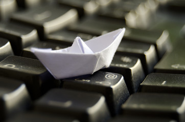 Obraz premium Origami boat on keyboard -Travel and navigating Internet concept