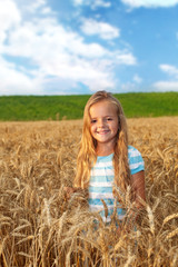 Naklejka na ściany i meble Golden hair girl on wheat field in late afternoon lights