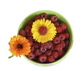 Ягоды малины в зеленой тарелке украшены цветами