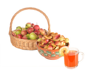 Apples in a basket, slices of apples and a juice glass
