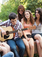 Cheerful teenagers playing guitar and singing
