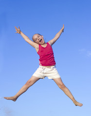 Little joyful girl jumps against blue sky