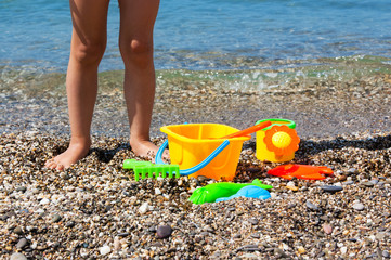 Child's legs and toys on the beach