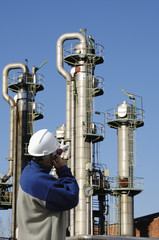 worker pointing at oil storage towers