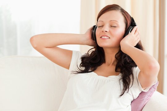 Dark-haired woman relaxing on a sofa with headphones