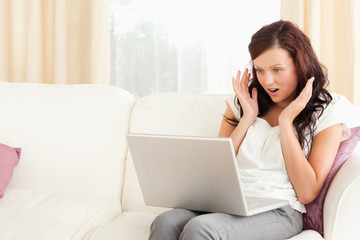 Amazed woman sitting on a sofa with a laptop