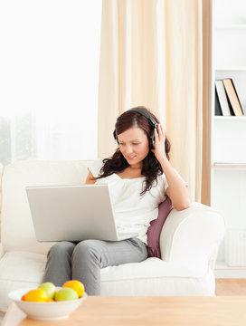 Gorgeous woman listening to music with a laptop on her lap