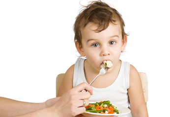 Little boy tasting vegetable salad