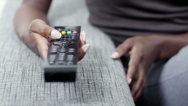 woman holding remote control and watching tv