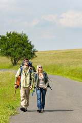 Hiking young couple backpack tramping asphalt road