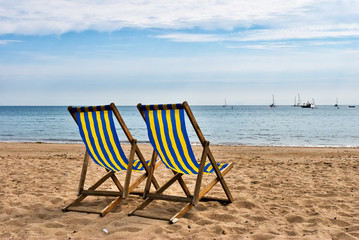 Two deckchairs on a sandy beach