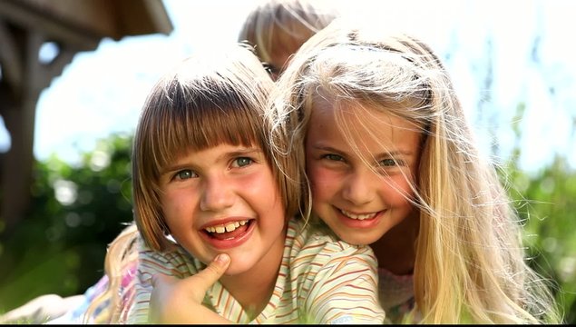 three girls lying in the grass and having fun smiling