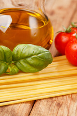 pasta, olive oil and tomatoes on the wood background
