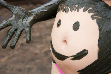 mud smiley on pregnant woman belly