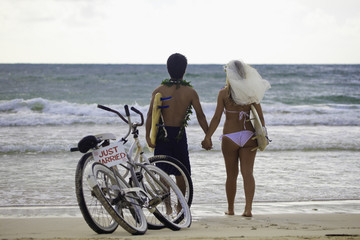 Obraz premium newlywed couple at the beach with surfboards and bikes