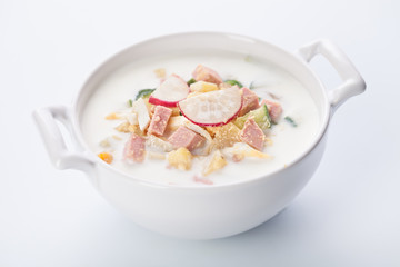 Cold kefir soup with eggs and sausage on white background