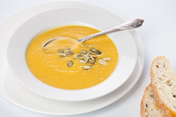 Pumpkin soup in white plate on white background
