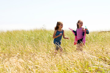 Naklejka na ściany i meble Children running in a grassy field.