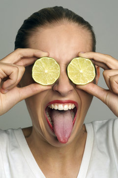 Junge Frau h&auml;lt sich Limonen vor die Augen