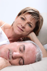 Obraz na płótnie Canvas Woman lying next to her sleeping husband