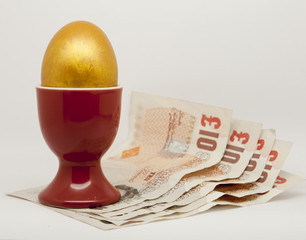 Golden Egg in an egg cup with money