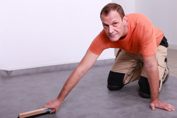 Man smoothing linoleum floor