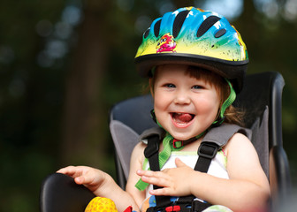 Little girl in the seat bicycle with a helmet on his head