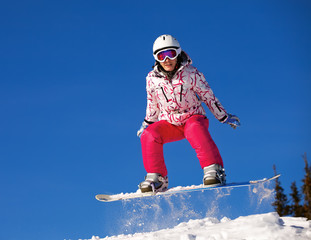 Fototapeta na wymiar Snowboarder skoki w powietrzu z błękitne niebo w tle
