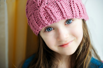 Close-up portrait of a child girl wearing pink knitted hat