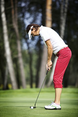 Fototapeta premium Female golfer concentrating on putting
