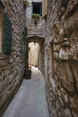 Narrow stone alley with a wooden konoba sign