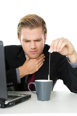 mann mit halsschmerzen auf arbeit tee trinken