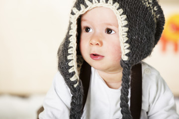 Baby boy with grey cap looking innocently.