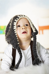 Baby boy with grey cap looking up.