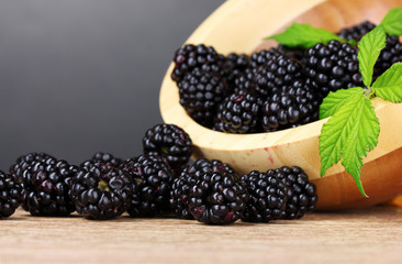 beautiful blackberries in wooden bowl on gray background
