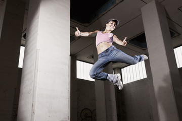 Female dancer jumping with thumbs up.