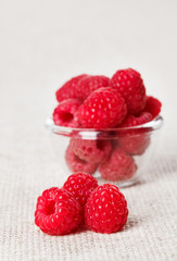 Still life with red raspberry and glass bowl on gray linen table