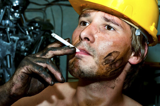 Worker covered in oil smoking