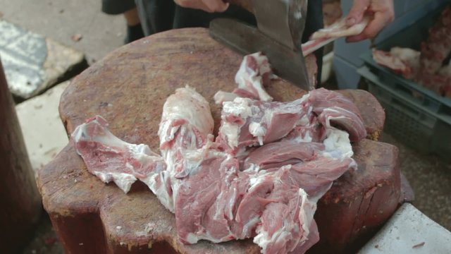 Butcher chopping bones of mutton legs with axe