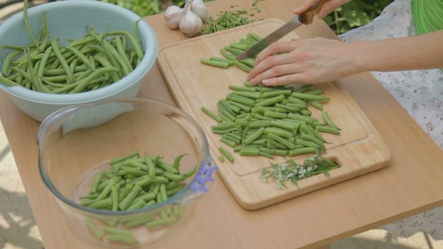 Preparing young green bunch of beans for slicing outdoors