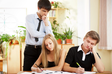 Teacher helping students in school classroom. Horizontally frame