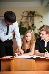 Teacher helping students in school classroom. Horizontally frame