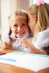 Obraz na płótnie Canvas Two little girls gossip in classroom