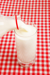 Pouring milk in a glass on checked tablecloth